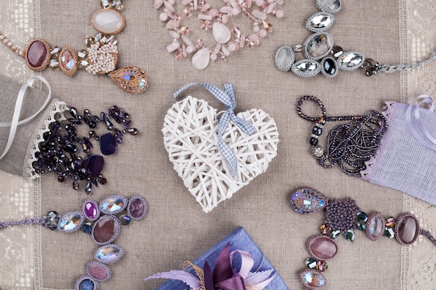Bijoux féminins et coeur décoratif sur nappe en lin