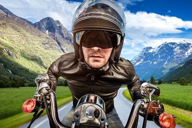 Biker en casque et veste en cuir racing sur route.