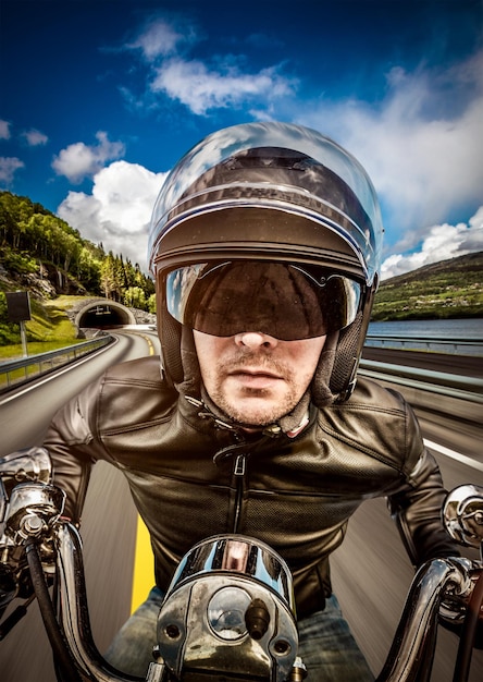 Biker en casque et veste en cuir racing sur route.