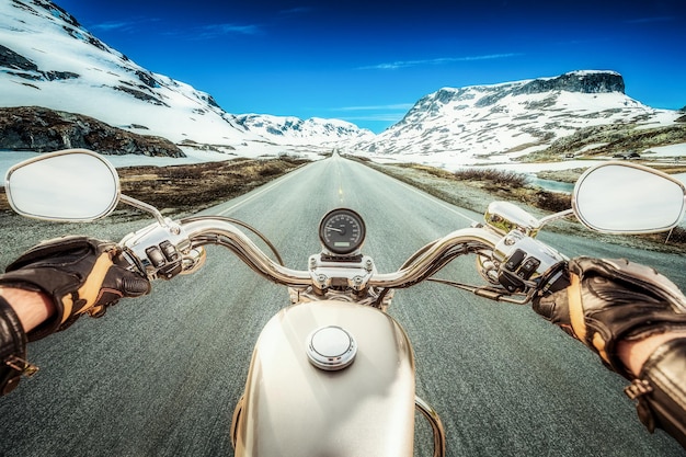 Biker conduit une moto sur une route glissante à travers un col de montagne en Norvège. Autour du brouillard et de la neige. Vue à la première personne.