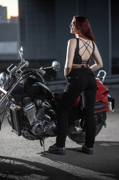 Biker fille posant sexuellement sur moto dans la ville de nuit