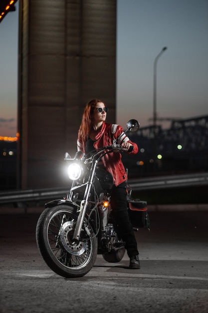 Biker fille posant sexuellement sur moto dans la ville de nuit