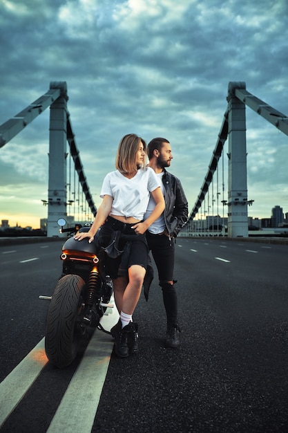 Biker homme et fille se tient sur la route et regarde au loin. Amour et concept romantique.