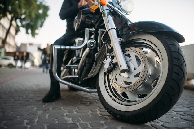 Biker en vêtements de cuir pose sur une moto