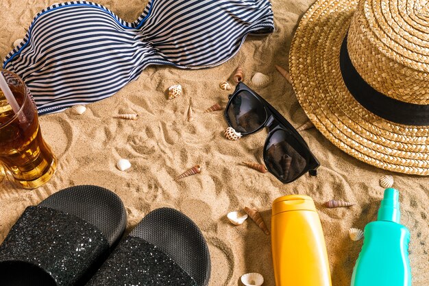 Bikini d'été et accessoires de plage élégants, tenue d'été de bikini de plage et sable de mer en arrière-plan, vue de dessus, concept