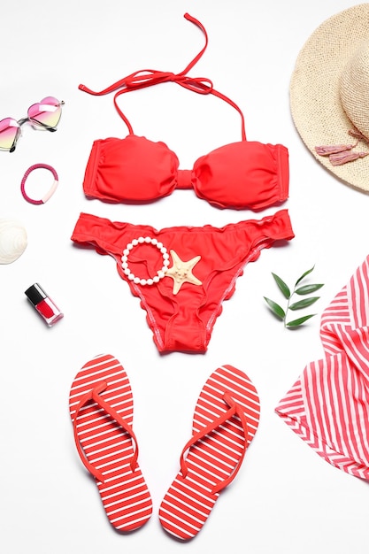 Bikini rouge et accessoires de plage sur fond blanc
