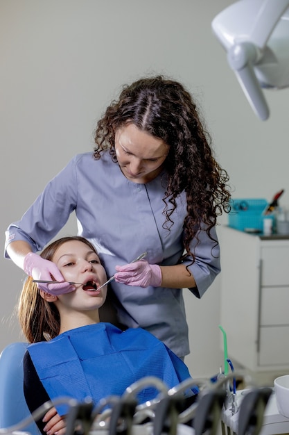 Bilan de santé. Le dentiste du centre de stomatologie examine les dents de la femme à l'aide d'outils dentaires.