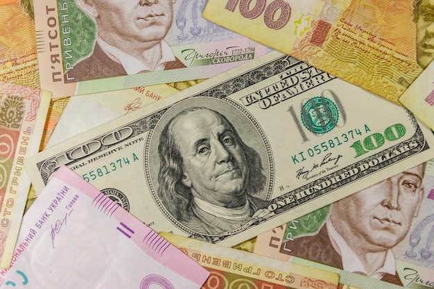 Billet de cent dollars sur fond de différents billets de banque en hryvnia ukrainienne