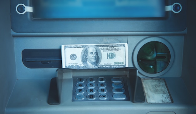 Billet de dollar assis sur un guichet automatique