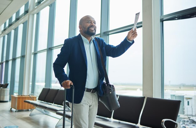 Photo billet d'homme noir et aéroport marchant jusqu'au départ pour un voyage d'affaires ou un voyage par les fenêtres heureux homme afro-américain avec sourire tenant un document ou une carte d'embarquement prêt pour le vol en avion