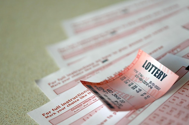 Le billet de loterie rouge se trouve sur des feuilles de jeu roses avec des numéros pour marquer pour jouer à la loterie Concept de jeu de loterie ou dépendance au jeu Gros plan