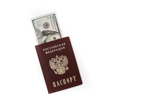 Des billets de 100 dollars en dollars américains se trouvent dans le passeport de la Fédération de Russie en gros plan sur un fond blanc Photo de haute qualité