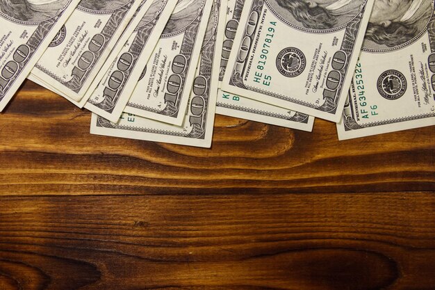 Billets de cent dollars sur un bureau en bois