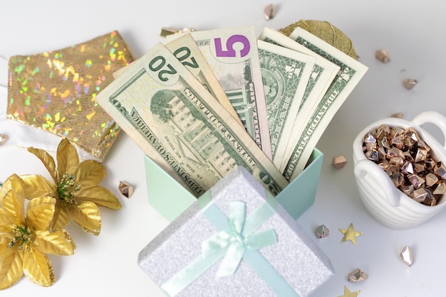 Billets d'un dollar dans une boîte cadeau comme cadeau de noël à côté d'accessoires de noël et d'un masque de protection