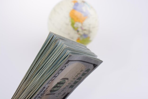 Billets en dollars américains à côté d'un globe modèle sur fond blanc
