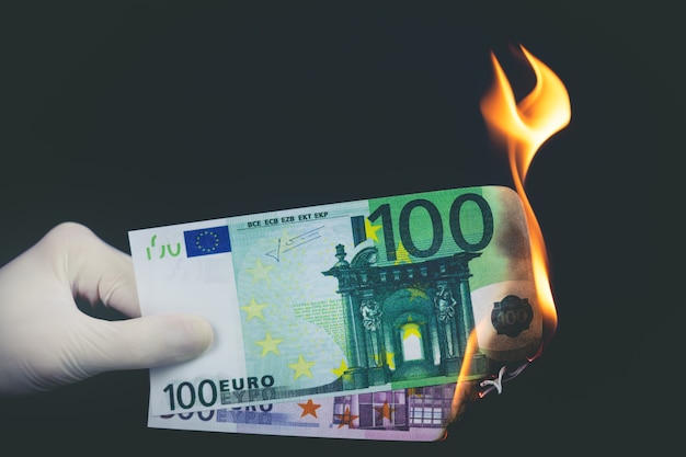 Les billets en euros brûlent sur fond noir. Notion de faillite.