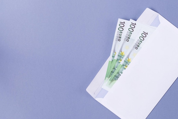 Billets en euros dans une enveloppe sur fond bleu - soncept financier.