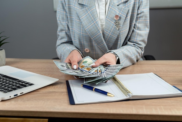 Des billets en papier dans les mains des femmes et un bloc-notes vide sur le bureau.