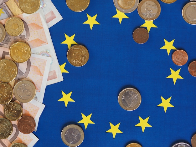 Billets et pièces en euros (EUR), monnaie de l'Union européenne sur le drapeau de l'Europe