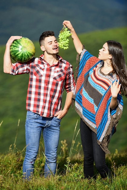 Bio et sain. couple hippie avec des fruits. vitamines et régimes amaigrissants. nourriture d'été. l'homme et la femme tiennent la pastèque. fille et garçon mangent des raisins. récolte d'été. week-end en famille en plein air. vacances d'été.