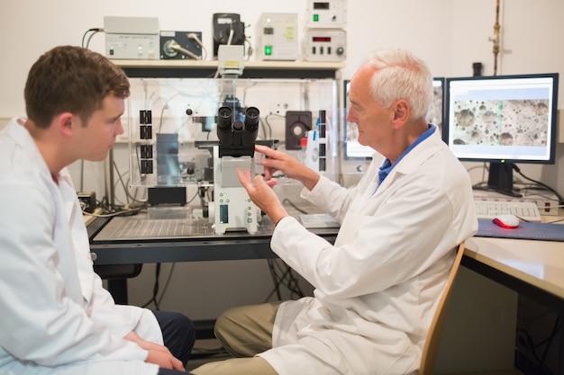 Biochimiste à l&#39;aide de gros microscope et ordinateur avec étudiant