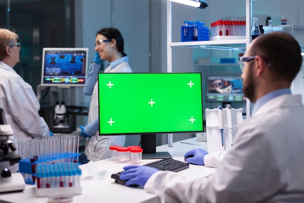 Biochimiste travaillant en laboratoire à l'aide d'un écran de maquette vert pour une expérience de biochimie avec un moniteur d'incrustation de chrominance