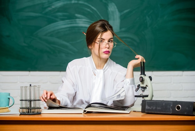 Biologiste chimiste avec microscope. Étudiant intelligent. Étudiez dur. Recherche scientifique. Étudiant en biologie s'asseoir fond de tableau de classe. Notion d'éducation. Femme enseignante ou étudiante assez adorable.