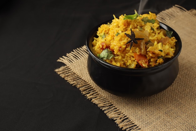 Biryani de légumes dans un bol noir sur fond noir, cuisine indienne épicée, hyderabadi biryani