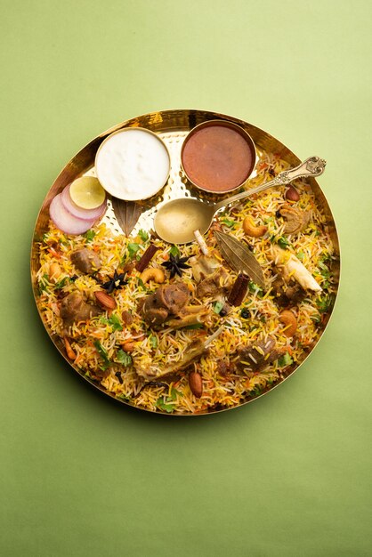 Biryani de mouton indien préparé dans du riz basmati servi avec une trempette au yogourt sur fond de mauvaise humeur, mise au point sélective