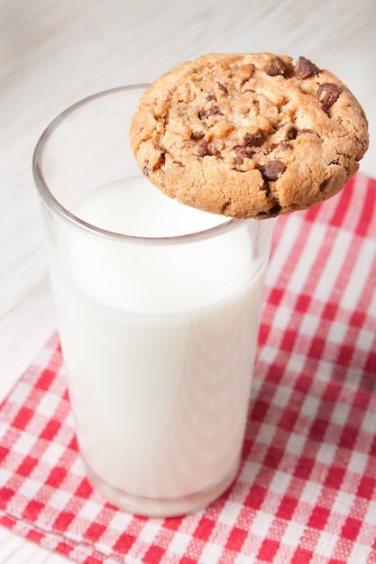 Biscuit au chocolat et verre de lait sur serviette sur table en bois blanc