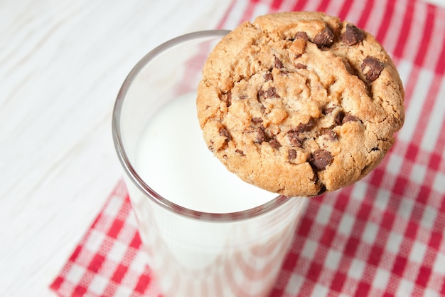 Biscuit au chocolat et verre de lait sur serviette sur table en bois blanc