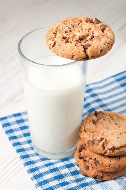 Biscuit au chocolat et verre de lait sur serviette sur table en bois blanc