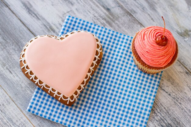 Biscuit coeur et pâte à cupcake rose sur serviette à carreaux bleu petites vacances pour que les proches trouvent la joie ...
