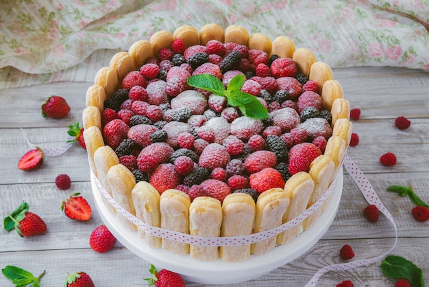 Le biscuit d'été négociation nue avec de la crème de mascarpone et des baies fraîches sur une surface en bois