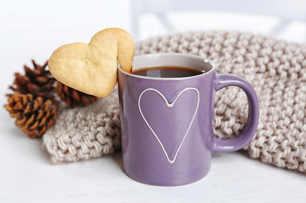 Biscuit en forme de coeur sur une tasse de café avec gros plan de tissu tricoté