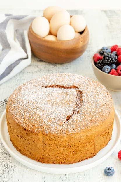 Biscuit ou génoise à la vanille classique fait maison saupoudré de sucre en poudre et de baies fraîches