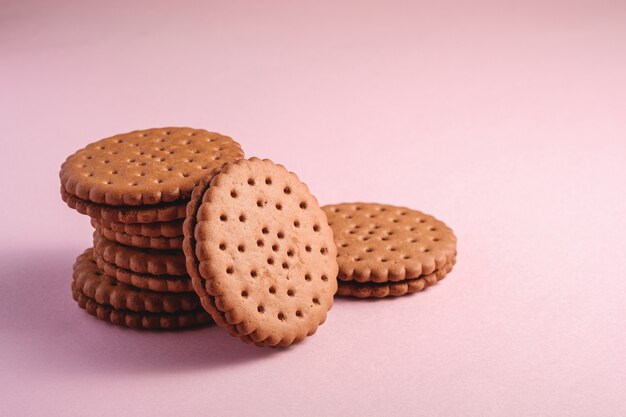 Biscuit sandwich au chocolat avec de la crème, des aliments empilés sucrés du magasin, sur une surface pastel rose, vue d'angle