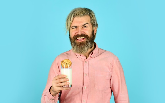 Biscuit de trempage sur du lait fermier heureux manger un dessert de biscuit homme barbu boire du lait utile avec de la pâtisserie Nourriture et boisson de Noël Biscuits de Noël et lait Concept de confort de Noël froid