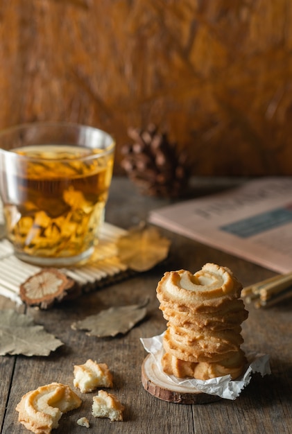 Biscuits Au Beurre Empilés Et Un Verre De Thé Sur Fond De Table En Bois, Photo Verticale.