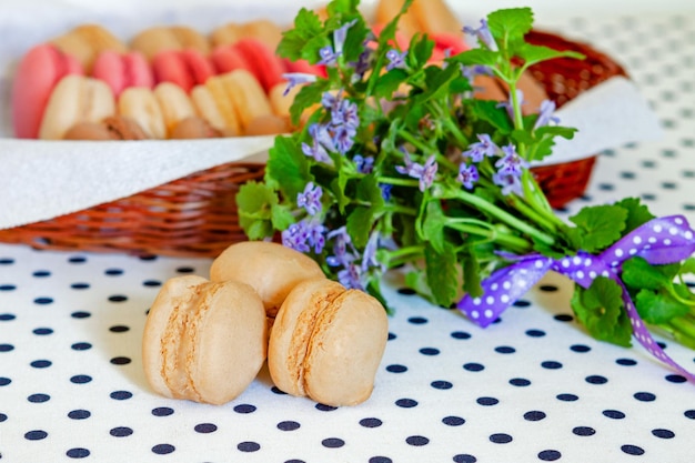 Biscuits au café macaron français dans un panier sur la table et un bouquet de fleurs violettes sauvages