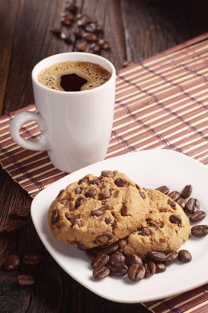 Biscuits au chocolat dans une assiette et une tasse de café chaud sur une serviette en bambou