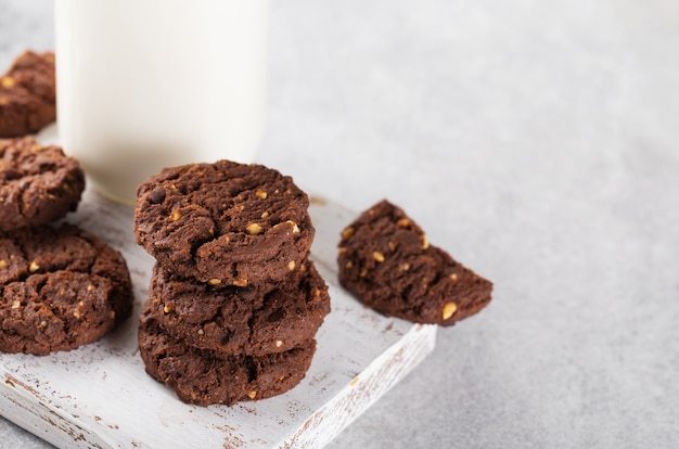 biscuits au chocolat avec du lait sur une planche en bois blanc fond gris espace horizontal pour le texte