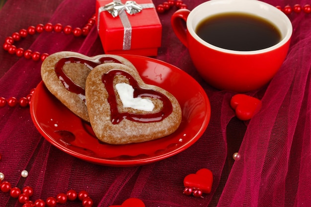 Biscuits au chocolat en forme de coeur avec une tasse de café sur une nappe rose close-up