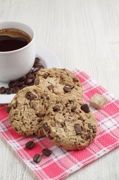 Biscuits au chocolat et tasse de café chaud sur une table en bois clair