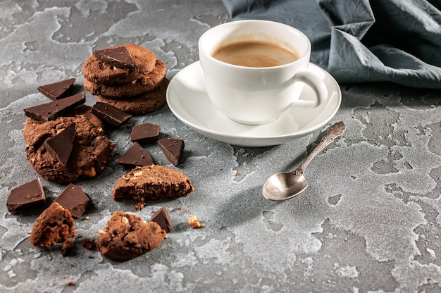 Biscuits Au Chocolat Et Une Tasse De Café Sur Un Fond De Béton Gris.