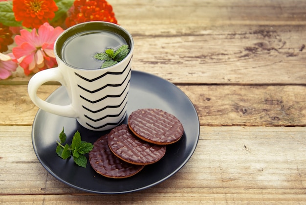 Biscuits au chocolat avec une tasse de thé sur fond en bois ancien.