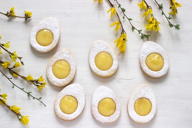 Biscuits au citron de Pâques faits maison et brindilles de fleurs de forsythia sur fond clair.