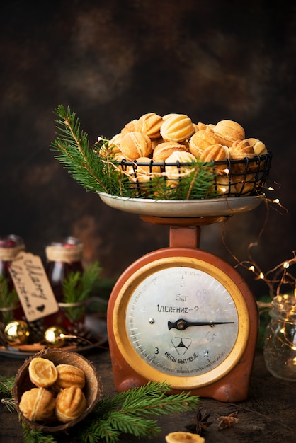 Biscuits au dessert de Noël noix avec du lait concentré bouilli sur un mur sombre avec des guirlandes et des décorations de Noël