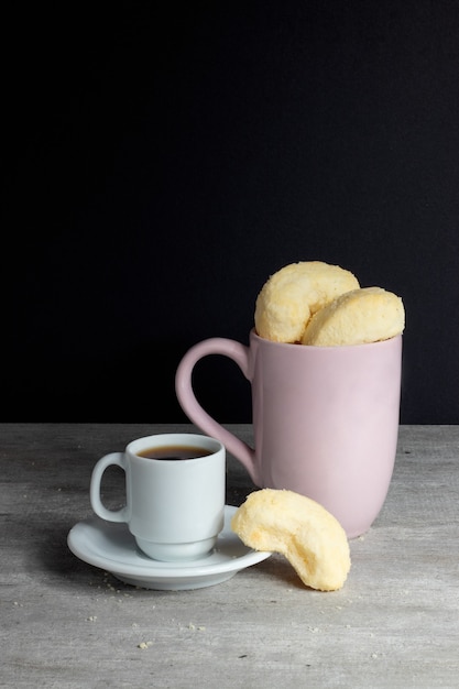 Biscuits au fromage traditionnels brésiliens servis avec une tasse de café.