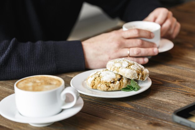 Biscuits au gingembre et mains d'homme tenant une tasse de café